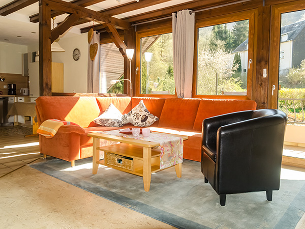 Sonniger Wohnraum der Ferienwohnung Burg Metternich mit Holzbalken und großen Fenstern