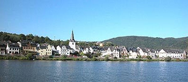 Briedern mit Kirchturm am Moselufer unter blauem Himmel